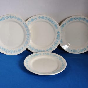 May include: Three white ceramic plates with a blue floral design around the rim.