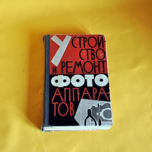 May include: A vintage book with a red, black, and white cover. The title, in Russian, reads "Construction and Repair of Photo Cameras." The cover features bold typography and graphic elements, set against a yellow background.