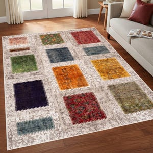 Puede incluir: Una alfombra rectangular con un diseño de patchwork. La alfombra presenta un fondo gris claro con un patrón floral repetido. Parches cuadrados de colores en tonos de rojo, verde, azul y naranja están dispersos por la alfombra.