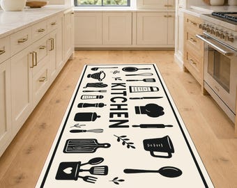 May include: A rectangular kitchen runner rug featuring a cream-colored background with a black border and various black kitchen utensil icons, including a whisk, rolling pin, and measuring cup, with the word KITCHEN printed vertically in the center.
