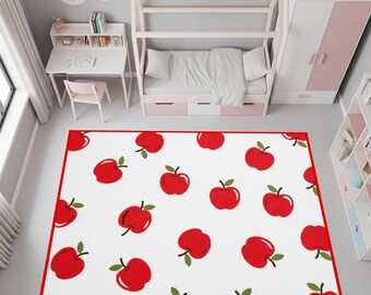 May include: A rectangular white rug with a red border and a pattern of red apples with green leaves. The rug is in a child's bedroom, with a bed, desk, and wardrobe visible in the background.