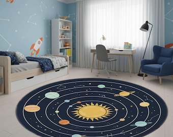 May include: A round, navy blue rug featuring a yellow sun at the center, surrounded by planets and white orbital paths. The rug is in a child's room with a blue wall decorated with rockets and constellations. The room includes a bed, desk, and chair.