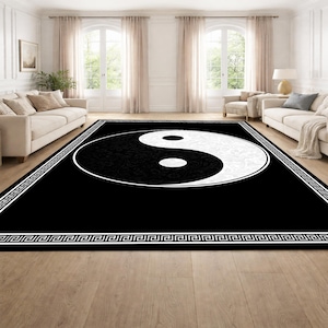 May include: A large black and white Yin Yang rug with a decorative border. The Yin Yang symbol is centered on the rug, with the black side featuring a floral pattern. The rug is placed in a living room setting.