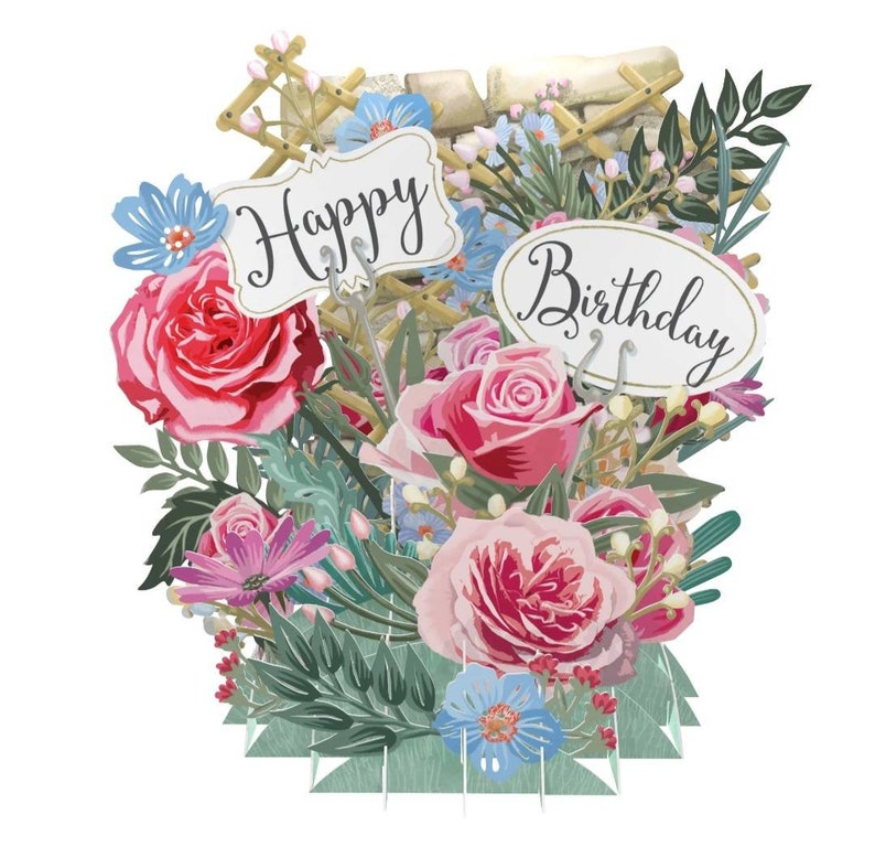 Peut inclure: Une carte pop-up 3D avec un bouquet de fleurs compos&eacute; de roses roses et rouges, de fleurs bleues et violettes et de feuilles vertes. La carte comporte deux pancartes qui disent "Happy" et "Birthday".