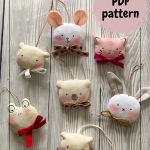 May include: A collection of handmade felt animal ornaments, including a bunny, cat, bear, and frog. Each ornament has a unique design with bows and string for hanging. The image includes the text "PDF pattern".