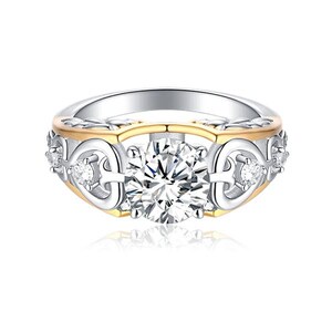 May include: A silver and gold ring with a large, clear, round-cut center stone. The ring features a decorative band with smaller accent stones and a gold-colored inner band. The design is intricate and elegant, suitable for special occasions.