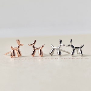 May include: Three pairs of balloon dog stud earrings. One pair is rose gold, one pair is silver, and one pair is a mix of rose gold and silver.