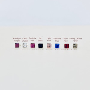 May include: A row of ten small square-shaped crystals in different colours, including amethyst purple, clear crystal, fuchsia pink, jet black, light pink, sapphire blue, siam red, and smoky quartz grey.