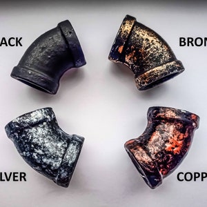 Puede incluir: Cuatro accesorios de tuber&iacute;a de metal en diferentes acabados: negro, plateado, bronce y cobre. Cada accesorio es un codo de 90 grados.