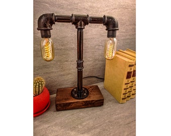 May include: A black metal table lamp with two Edison bulbs. The lamp has a wooden base and is made to look like pipes.