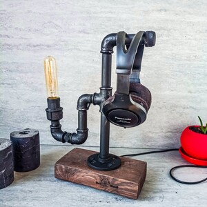 Puede incluir: Soporte para auriculares de metal negro con base de madera. El soporte tiene forma de tubo y tiene una bombilla unida. La base est&aacute; grabada con "Real Wood".