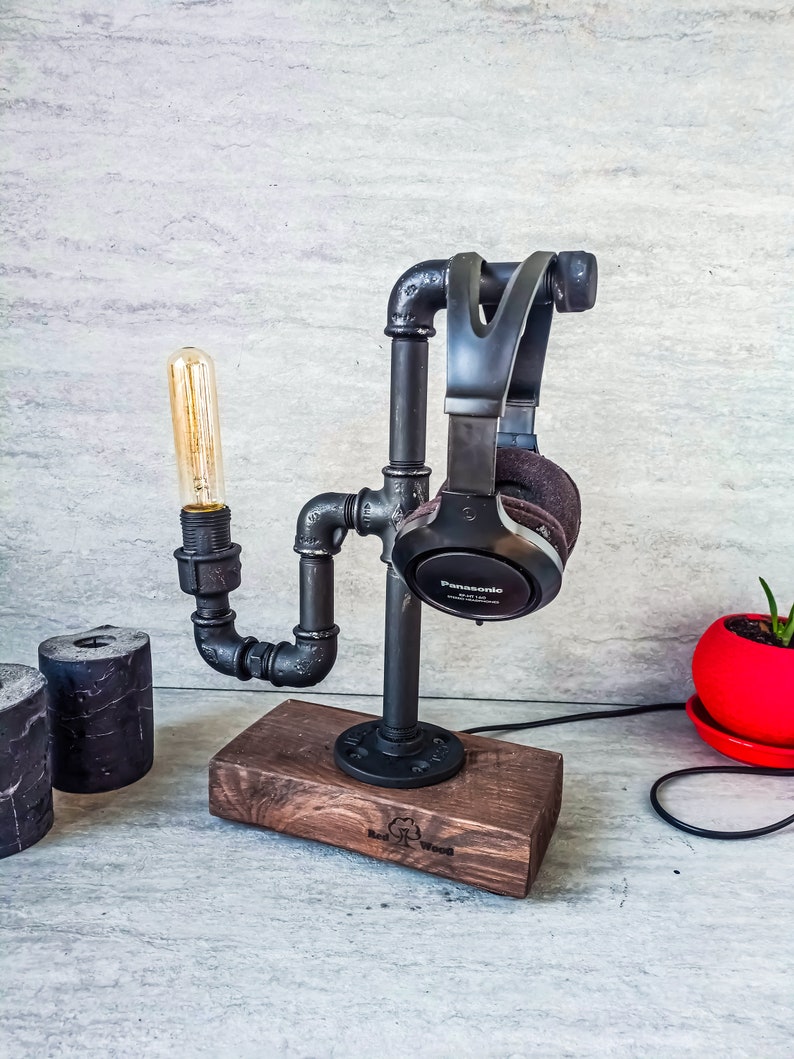 Puede incluir: Soporte para auriculares de metal negro con base de madera. El soporte tiene forma de tubo y tiene una bombilla unida. La base est&aacute; grabada con "Real Wood".