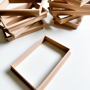 May include: A stack of six brown plastic rectangular cookie cutters, with one cutter lying flat on a white surface.