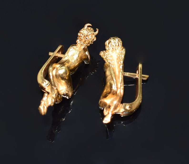 May include: A pair of gold-toned earrings featuring a cherub design. Each earring has a hook closure.