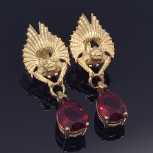May include: Gold tone earrings with a bat design and dangling red teardrop shaped stones.