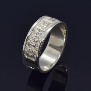Peut inclure: Une bague en argent avec le mot "Teufel" gravé autour de la bande.