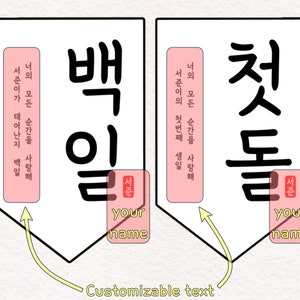 May include: Two white banners with black Korean characters, "Baek Il" and "Cheot Dol", meaning "100 days" and "first birthday".  Each banner has a pink rectangle with the text "Your name" and "Seojoun" in Korean.