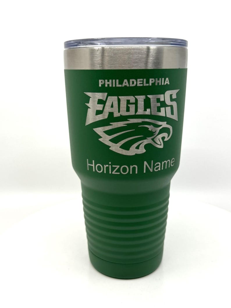 Pu&ograve; includere: Un bicchiere in acciaio inossidabile verde con coperchio trasparente, caratterizzato dal logo dei Philadelphia Eagles inciso in argento. Il testo PHILADELPHIA EAGLES &egrave; posizionato sopra l'emblema dell'aquila, con il testo Horizon Name inciso sotto.