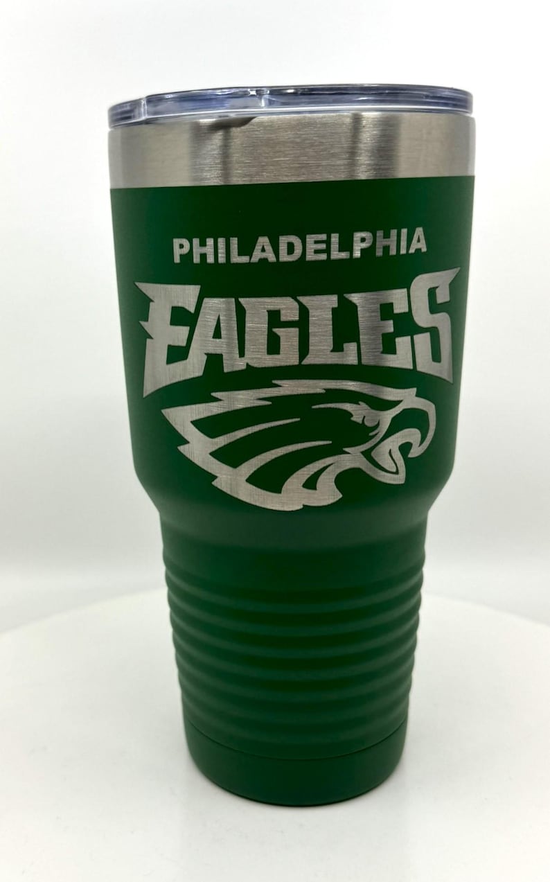Pu&ograve; includere: Un bicchiere in acciaio inossidabile verde bosco con coperchio in plastica trasparente e il logo e il nome Philadelphia Eagles incisi in argento. Il bicchiere presenta una base scanalata testurizzata e una parte superiore liscia con bordo metallico.