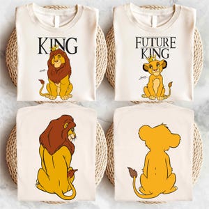 May include: Two white t-shirts with a lion king theme. The first shirt says "KING" with a cartoon lion wearing a crown. The second shirt says "FUTURE KING" with a cartoon lion cub wearing a crown.