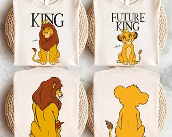 May include: Two white t-shirts with a Lion King theme. The first shirt says "KING" with a cartoon lion wearing a crown. The second shirt says "FUTURE KING" with a cartoon lion cub wearing a crown.