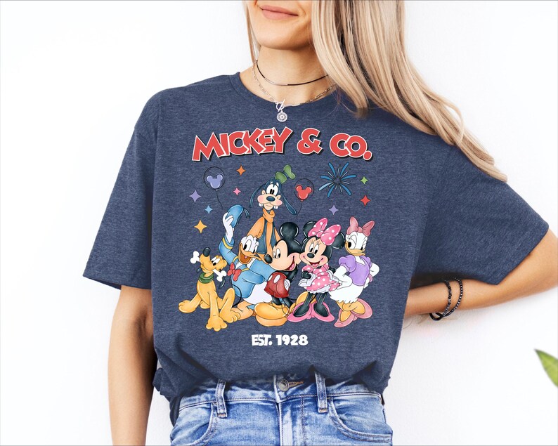 A woman wearing a blue t-shirt with a graphic of Disney characters and text.