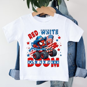 A white t-shirt with a graphic design featuring a character riding a vehicle with the text "RED WHITE BOOM" printed on it.