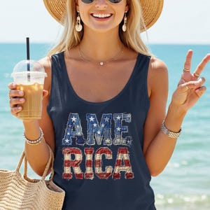 Könnte beinhalten: Ein ärmelloses, marineblaues Tanktop mit dem Wort AMERICA in einem abgenutzten Patchwork-Design. Die Buchstaben A, M und E sind in einem blauen Jeansmuster mit weißen Sternen gestaltet, während die Buchstaben R, I, C und A rote und weiße Streifen aufweisen.