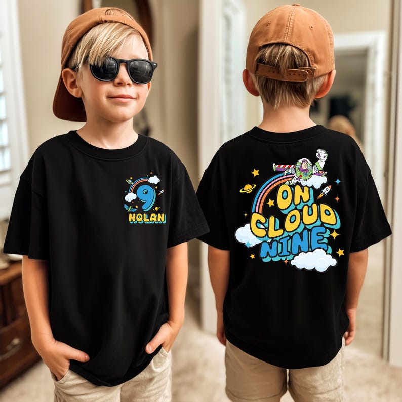 A young boy wearing a black t-shirt with a graphic design on the back, including a character and the text "ON CLOUD NINE".