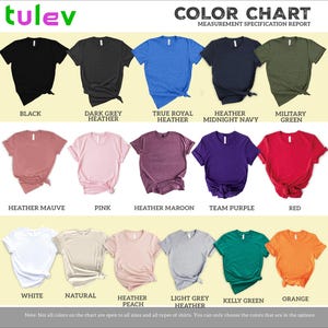 The image is a color chart that displays various t-shirt colors and their corresponding names. The chart includes a collection of t-shirts in different colors, such as black, dark grey, true royal heather, heather maroon, team purple, pink, peach, light grey, kerry green, and orange. The chart provides a visual representation of the different color options available for t-shirt designs.