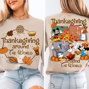 May include: Beige sweatshirt featuring the text "Thanksgiving around the World" and cartoon graphics. The front shows a pumpkin, turkey, and other Thanksgiving icons. The back displays Disney characters celebrating.