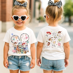 A young girl wearing a white t-shirt with a cartoon character design and heart-shaped sunglasses, standing on a street.