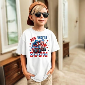 A young boy wearing a white t-shirt with a graphic design and sunglasses stands in a room.