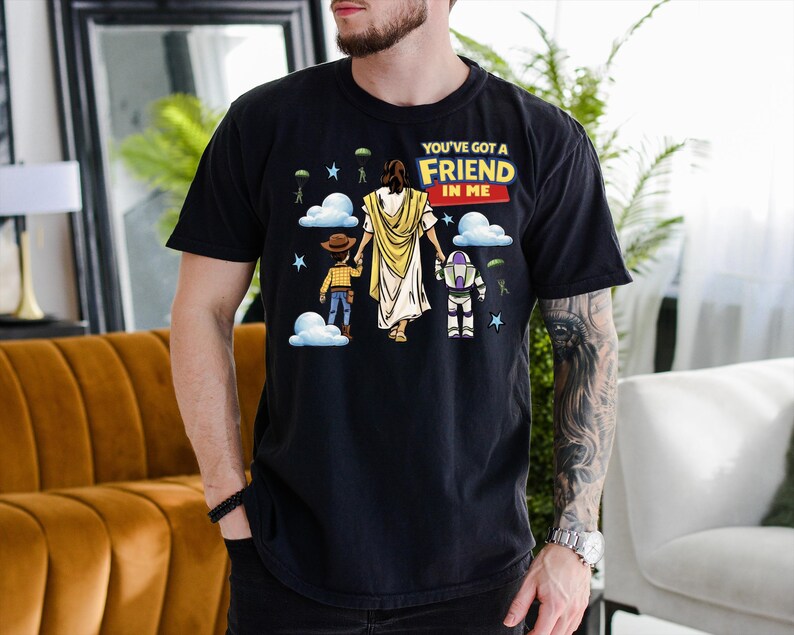 A man wearing a black t-shirt with a graphic design depicting a cartoon character and the text "You've got a friend in me"