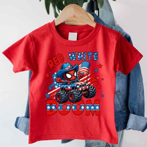 A red t-shirt with a graphic design featuring a Spider-Man character and patriotic symbols, such as an American flag and stars, along with the text "RED WHITE BOOM".