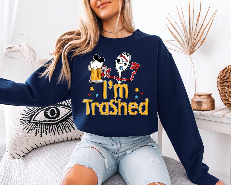 A woman wearing a navy blue sweatshirt with a graphic design of a character from the Toy Story franchise and the text "I'm Trashed" printed on it.