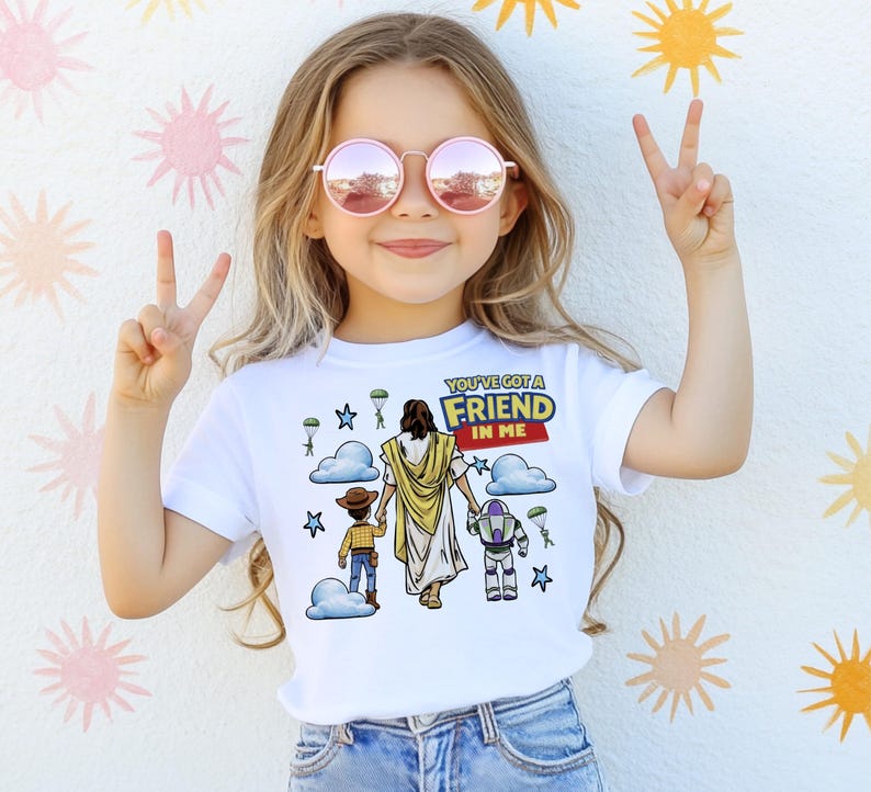 A young girl wearing a white t-shirt with a graphic design and making a peace sign with her hands.
