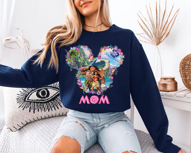 a woman sitting on a bed wearing a mickey mouse sweatshirt
