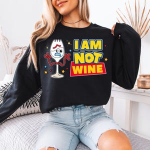 A woman wearing a black sweatshirt with a graphic design featuring a cartoon character and text.