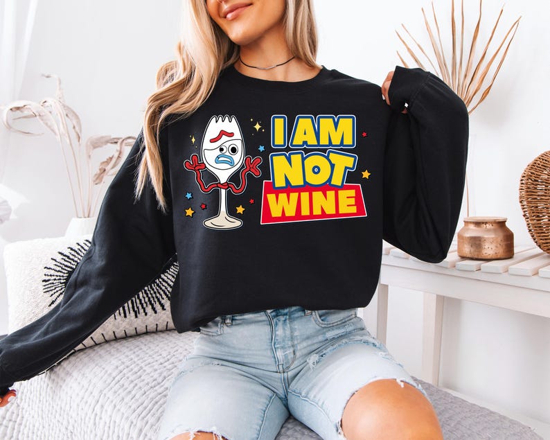 A woman wearing a black sweatshirt with a graphic design featuring a cartoon character and text.