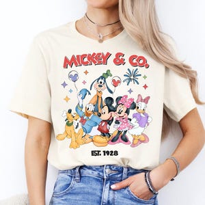 A woman wearing a white t-shirt with a graphic of Disney characters Mickey Mouse and Co.