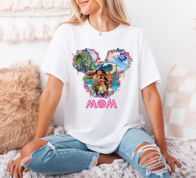 a woman sitting on a bed wearing a mickey mouse shirt