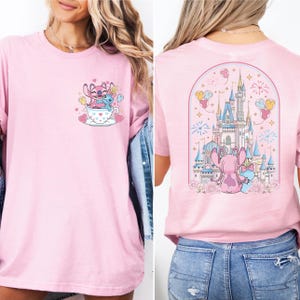 A woman wearing a pink t-shirt with a castle and a cup of tea graphic on the front and a castle and a cup of tea graphic on the back.