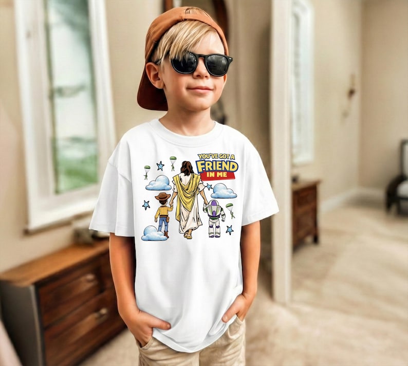 A young boy wearing a white t-shirt with a graphic design and sunglasses stands in a room.