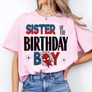 A woman wearing a pink t-shirt with the text "SISTER OF THE BIRTHDAY" printed on it.