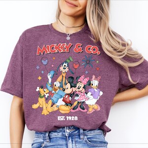 A woman wearing a purple t-shirt with a graphic of Disney characters Mickey Mouse and Co.