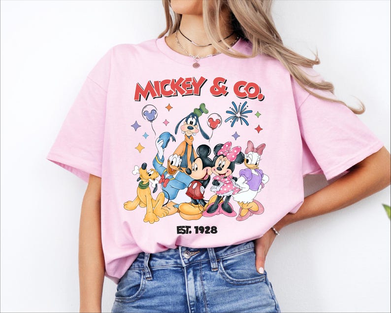 A woman wearing a pink t-shirt with a graphic of Disney characters Mickey Mouse and Co.
