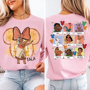 Puede incluir: Sudadera rosa con un gr&aacute;fico de un personaje de Disney en la parte delantera y un collage de personajes de Disney en la parte trasera. El gr&aacute;fico de la parte delantera presenta a una mujer con un lazo en la cabeza y el texto "Tala". El gr&aacute;fico de la parte trasera presenta un collage de personajes de Disney de la pel&iacute;cula Moana, incluyendo a Maui, Moana, Pua, Hei Hei, Gramma Tala, Chief Tui y Baby Moana.