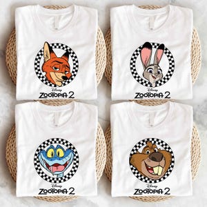 four white t-shirts with cartoon character logos from the Disney movie "Zootopia 2".