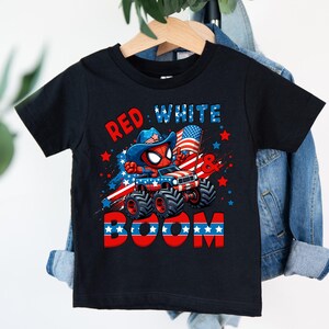 A black t-shirt with a graphic design featuring a Spider-Man character, a Jeep, and the text "RED WHITE BOOM" against a patriotic background.